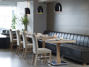 Un comedor moderno con una mesa larga, varias sillas y un sofá.