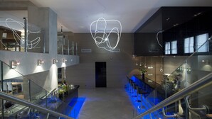 A modern hotel lobby with a central staircase, glass railings, and contemporary lighting fixtures. - Anatolia Hotel (Komotini)
