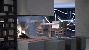 A modern interior with a central fire feature, seating area, and contemporary decor. - Anatolia Hotel (Komotini)