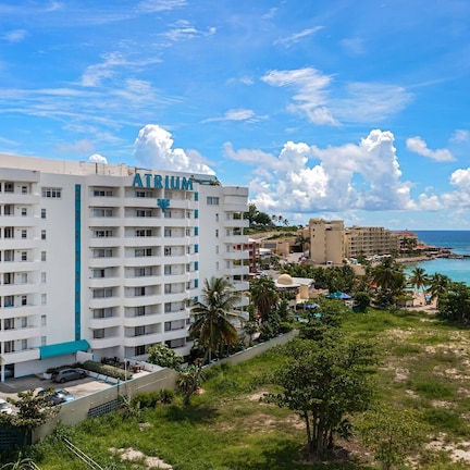 A multi-story hotel with balconies, a beach view, and a clear sky.