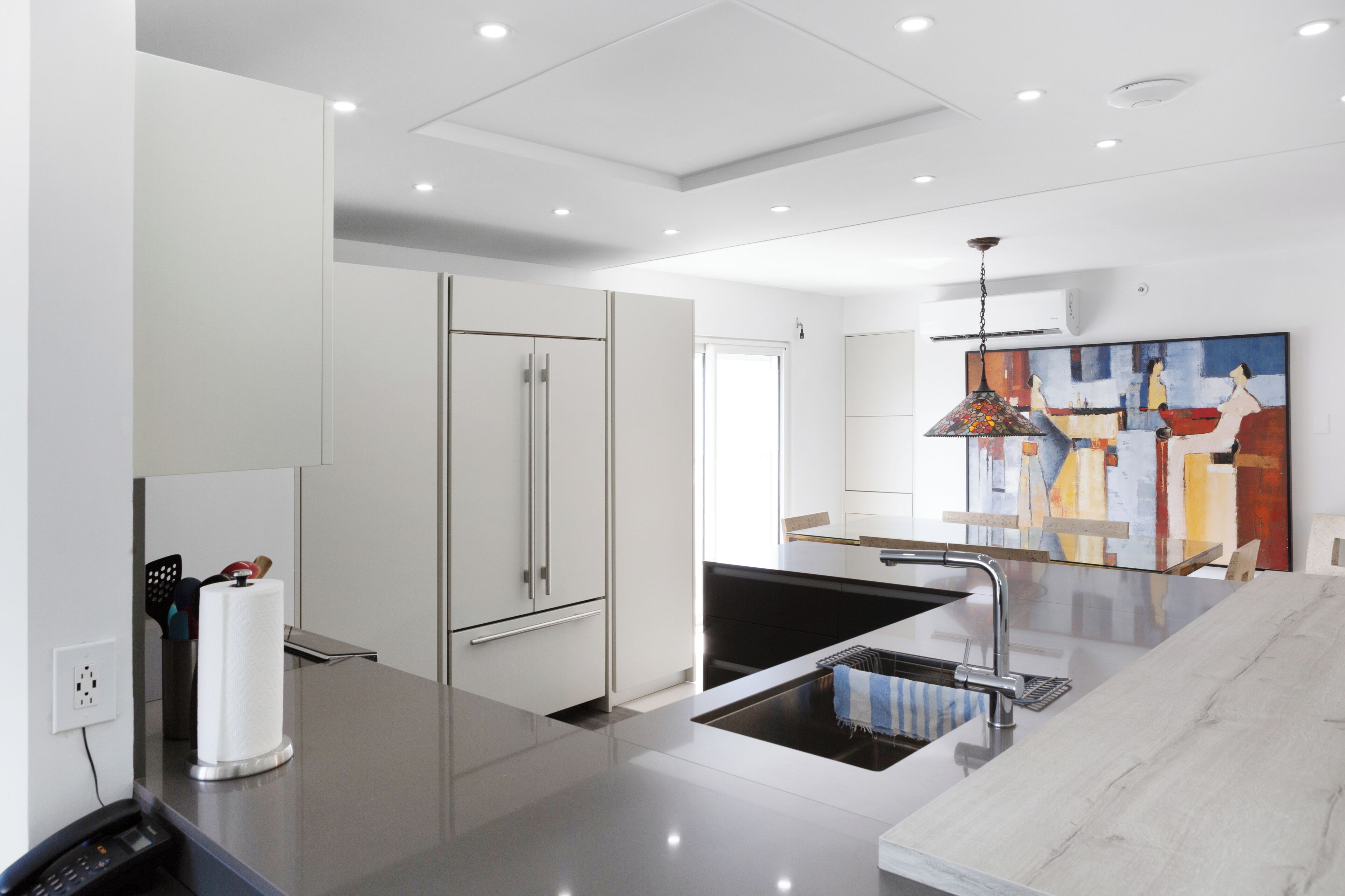 A modern kitchen with white cabinetry, a stainless steel refrigerator, and a black sink.