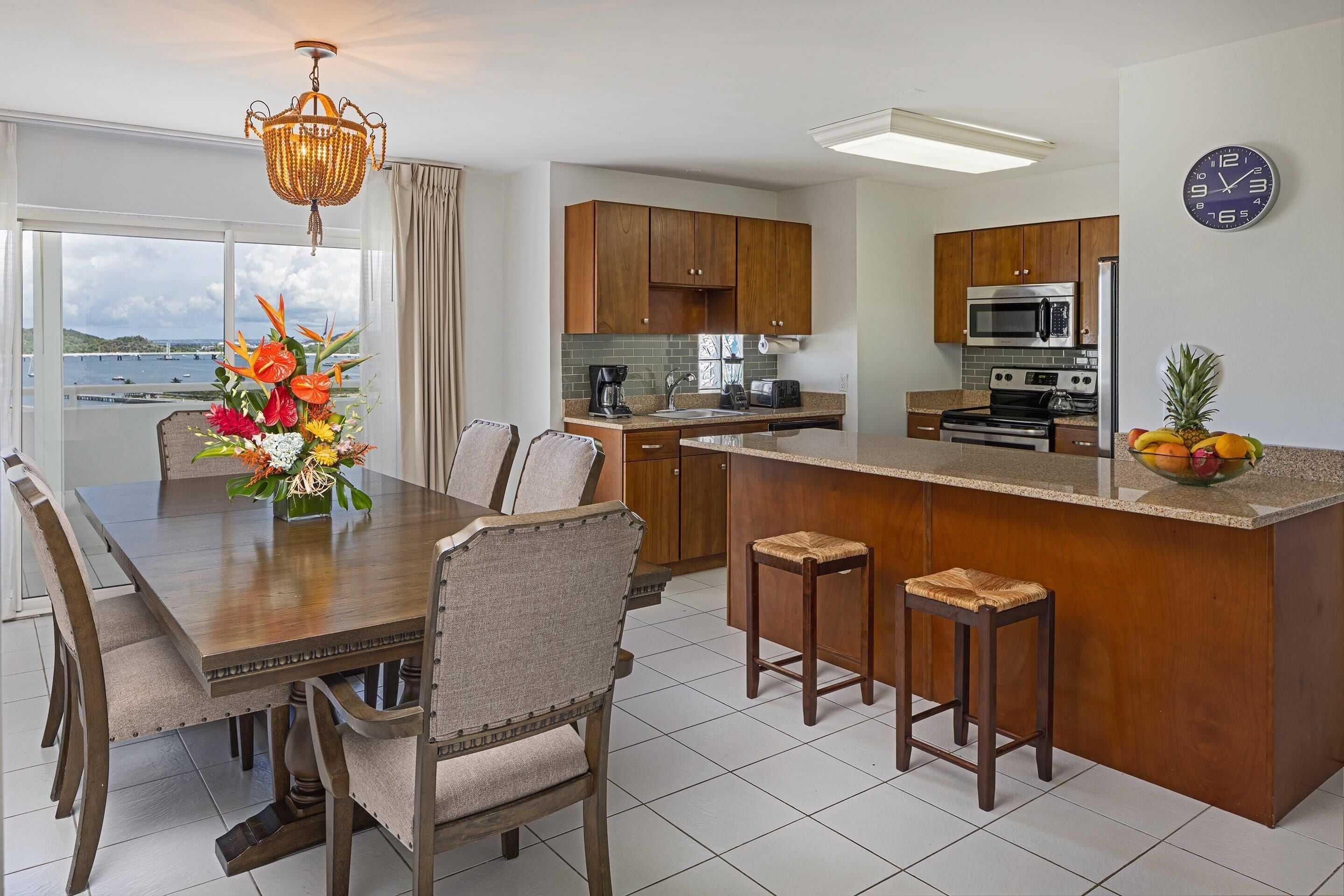 A modern kitchen with wooden cabinets, a central island, and a dining area with a table and chairs.