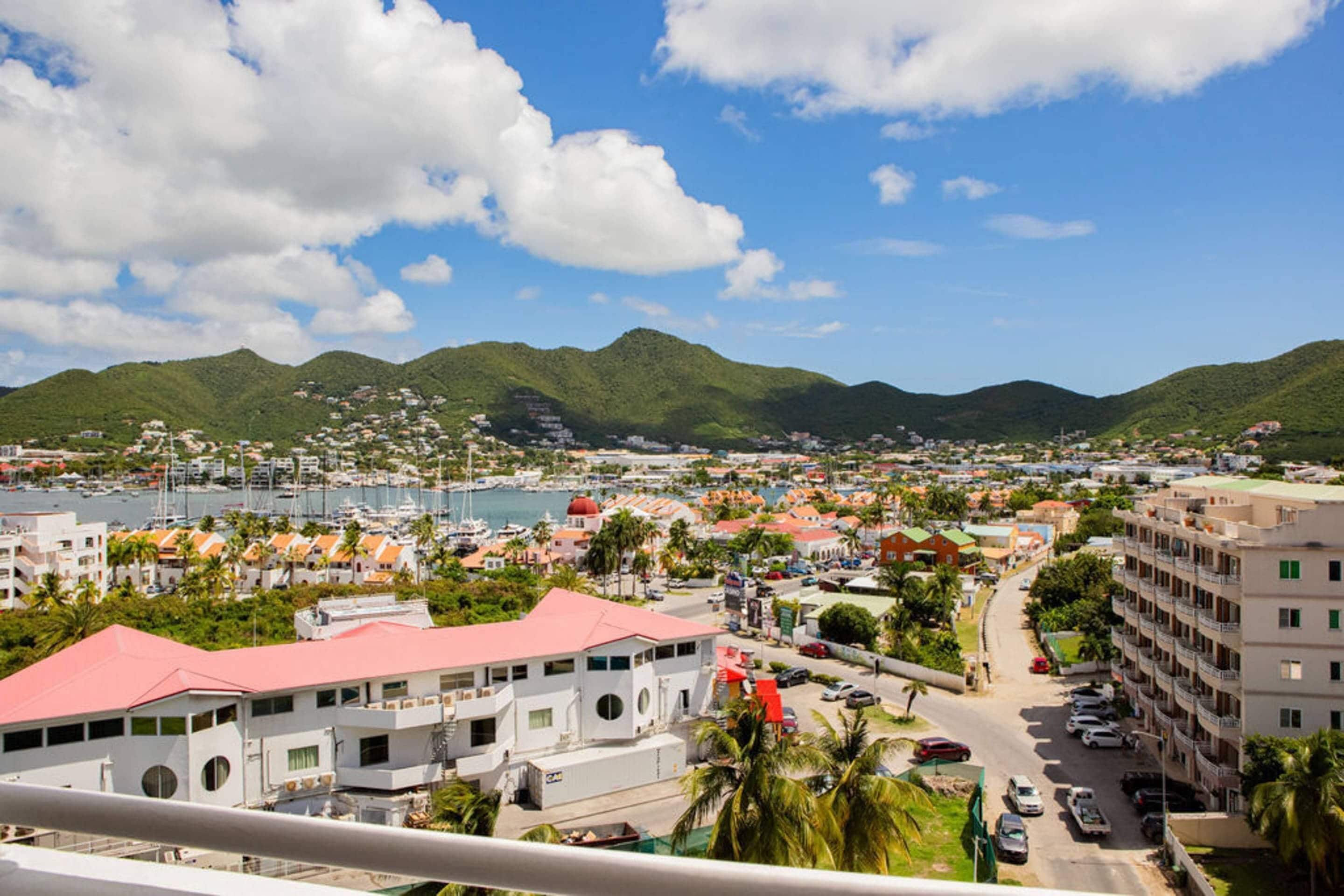 A coastal town with buildings, a marina, and mountains in the background.