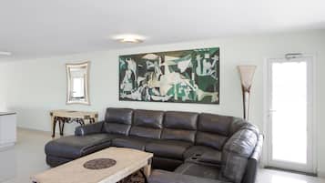 Una sala de estar moderna con un sofá modular, una mesa de centro, un cuadro en la pared y una lámpara de pie.