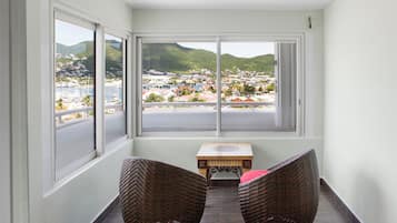 A corner room with a view of a coastal town, wicker chairs, and a small wooden table.