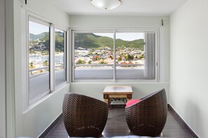A corner room with a view of a coastal town, wicker chairs, and a small wooden table. - The Atrium Beach Resort and Spa, an Ascend Collection Resort (Simpson Bay)
