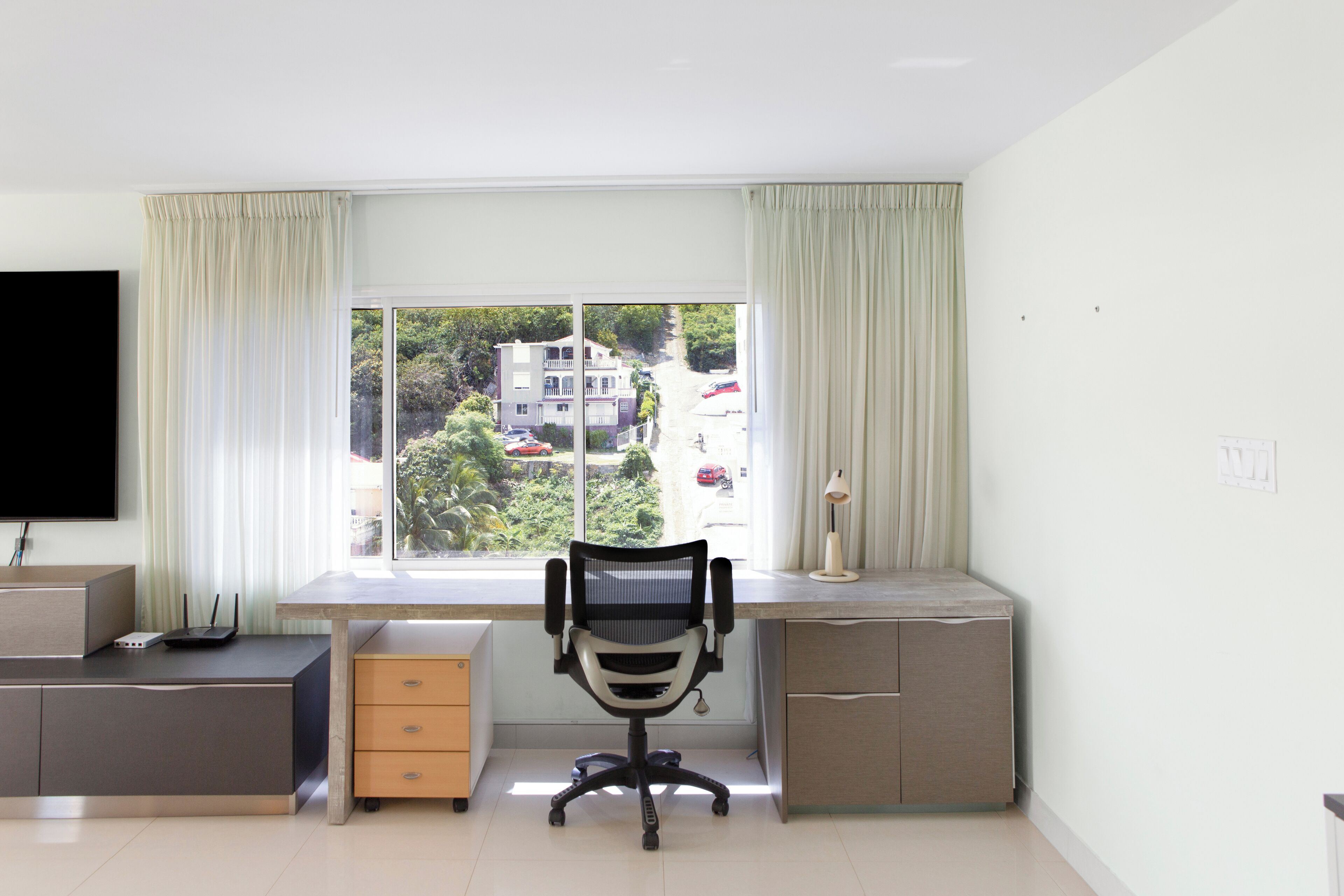 Un espacio de oficina moderno con escritorio, silla y televisor integrado.