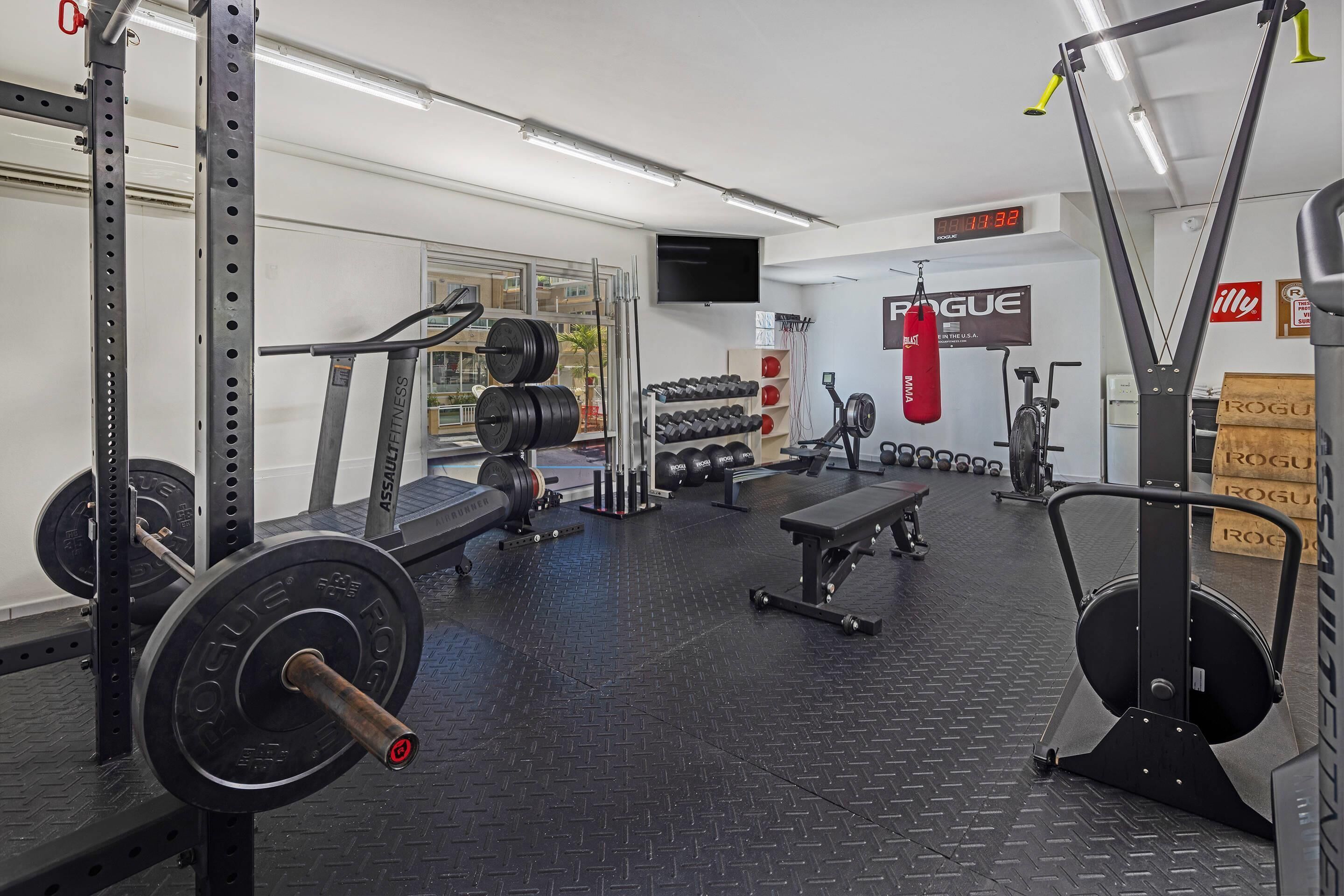 A gym with weightlifting equipment, treadmills, and dumbbells.