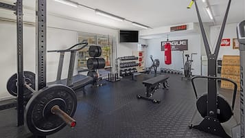 A gym with weightlifting equipment, treadmills, and dumbbells.