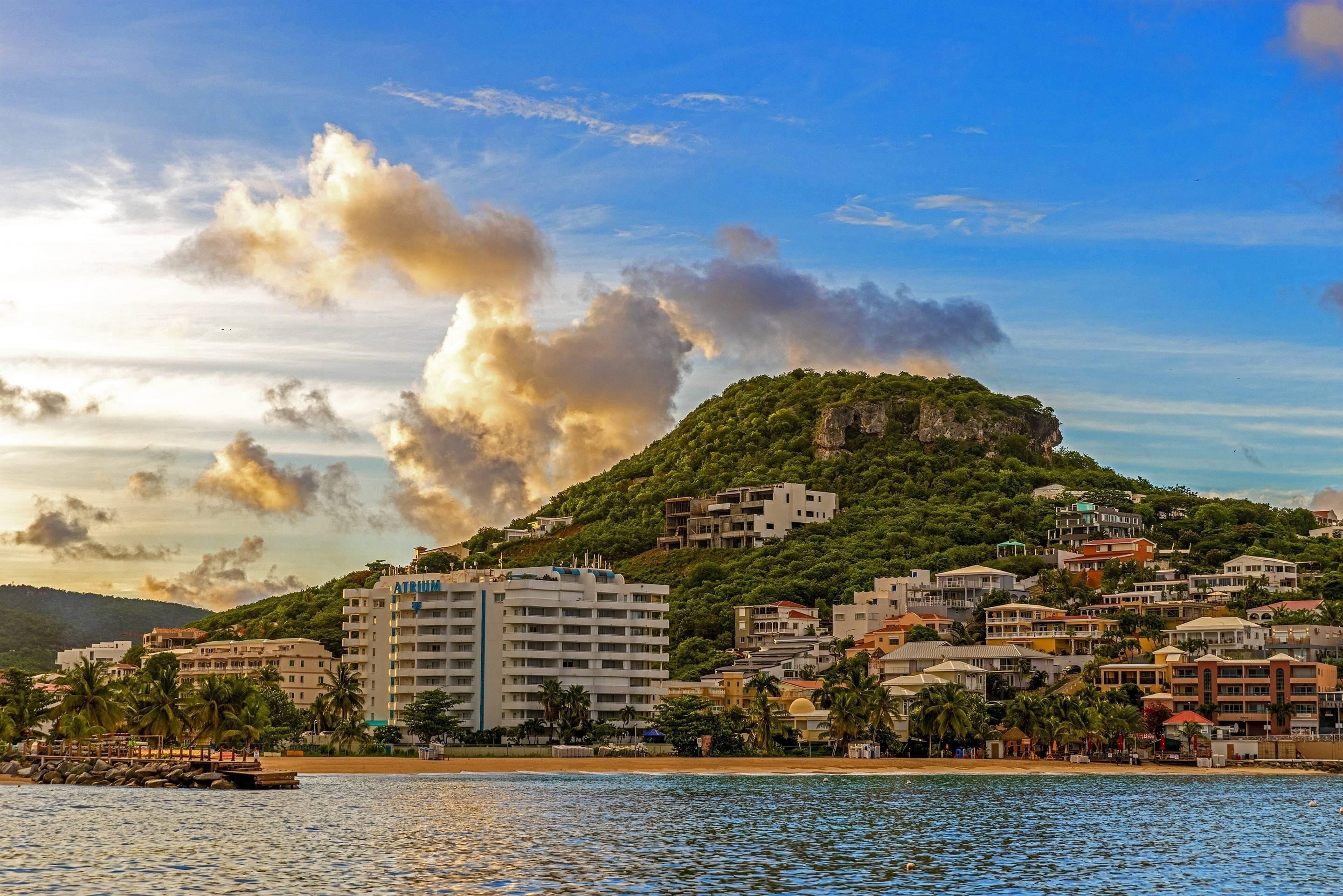 A coastal town with a prominent hill, buildings, and a beach.
