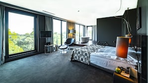 A modern hotel room with a large bed, a desk with a computer, a chair, a TV, and a bathtub. - Hotel mOdus (Varna)