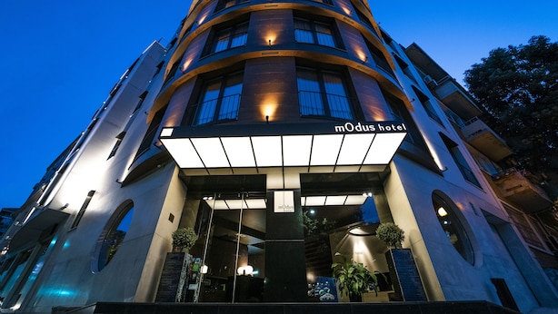 A modern hotel with a curved facade, illuminated signage, and a prominent entrance. - Hotel mOdus (Varna)