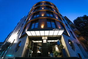 A modern hotel with a curved facade, illuminated signage, and a prominent entrance. - Hotel mOdus (Varna)