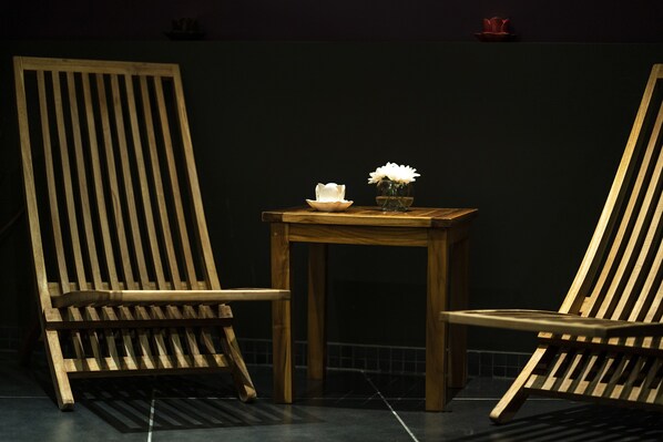 Two wooden chairs with a small table between them, featuring a white flower and a candle.