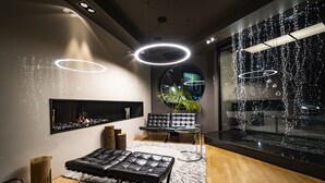 A modern living room with a fireplace, leather sofa, and a glass coffee table. - Hotel mOdus (Varna)