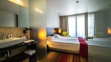 A hotel room with a bed, a bathroom with a sink, and a mirror.