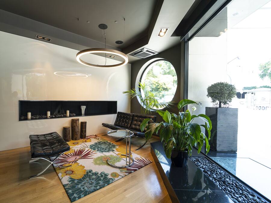 Una sala de estar moderna con piso de madera, un espejo redondo, un sofá, una mesa de centro y una planta en maceta.