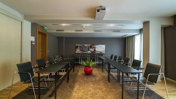Ein Konferenzraum mit langem Tisch, Stühlen, einer roten Pflanze und einer Whiteboard-Tafel.