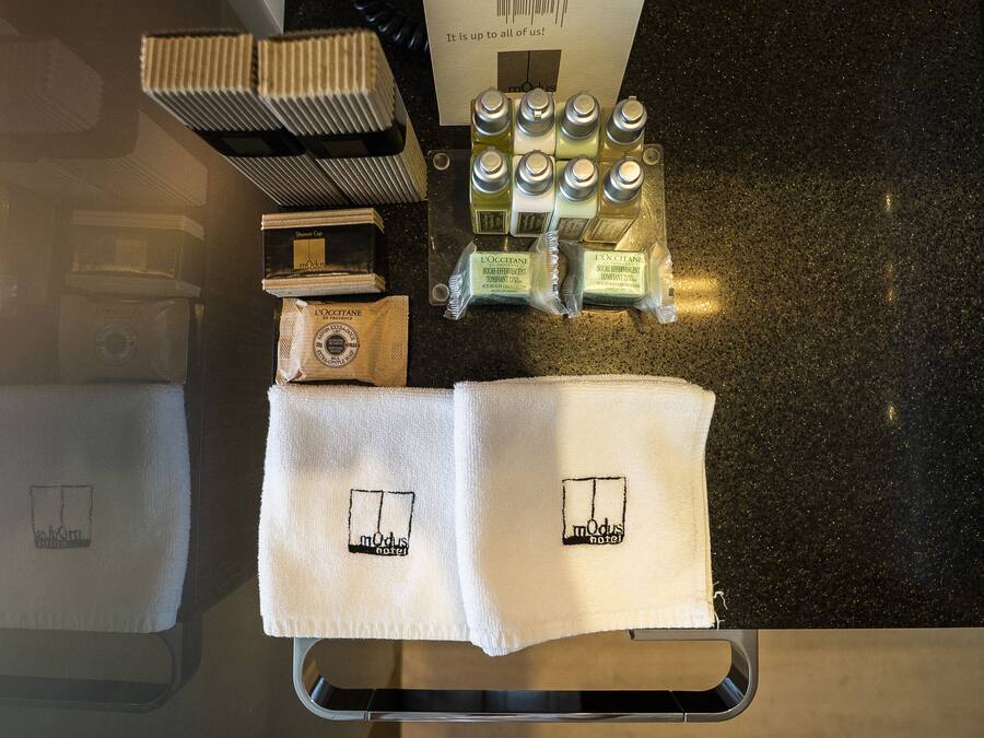 Ein Hotelzimmer mit Minibar, Pflegeprodukten und Handtüchern mit dem Hotel-Logo.