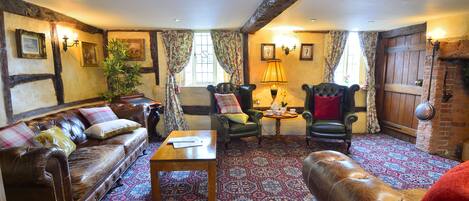 A traditional room with a leather sofa, a green armchair, and a patterned carpet.