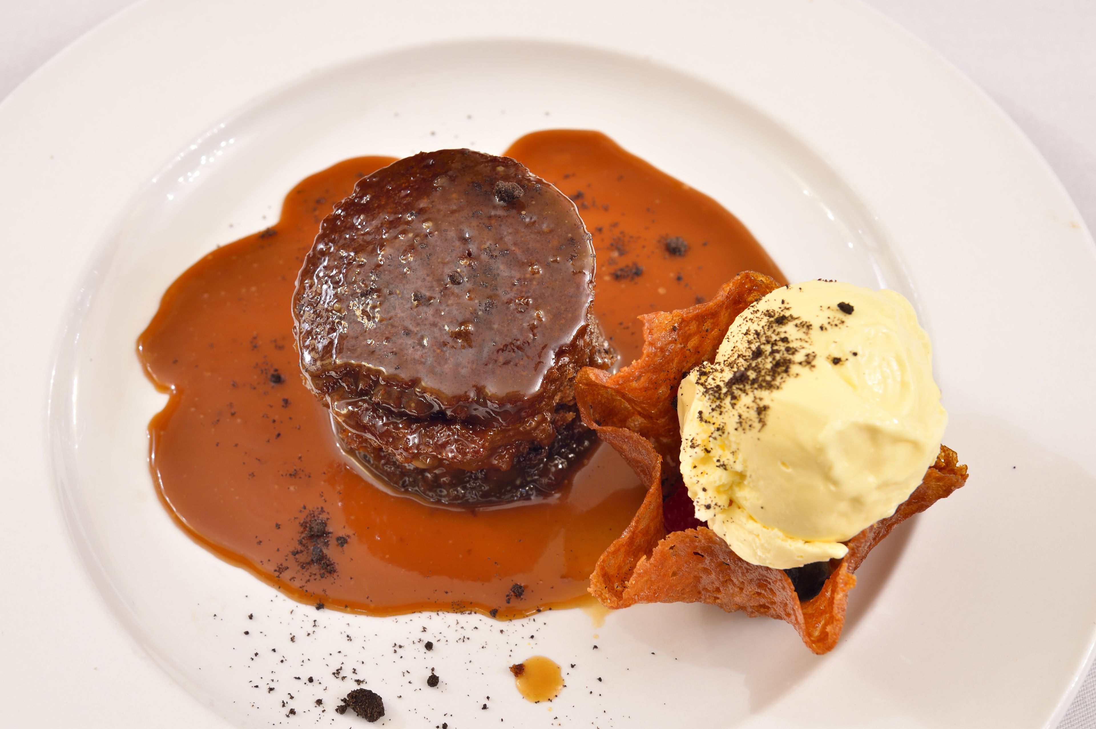 Un plato de postre con un dulce de chocolate y una bola de helado de vainilla.