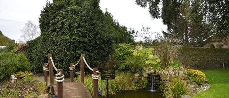 A wooden bridge over a pond with a sign for young children and an adult.
