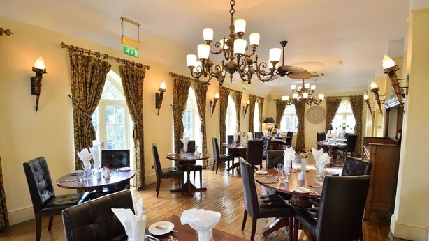 A dining area with multiple tables, chairs, and chandeliers. - Angmering Manor (Littlehampton)