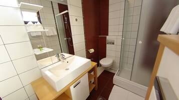 A modern bathroom with a white sink, mirror, and shower.