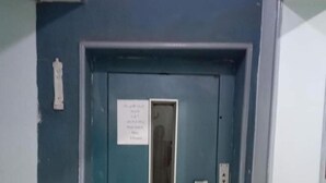 A blue elevator door with a sign above it and a control panel to the right.