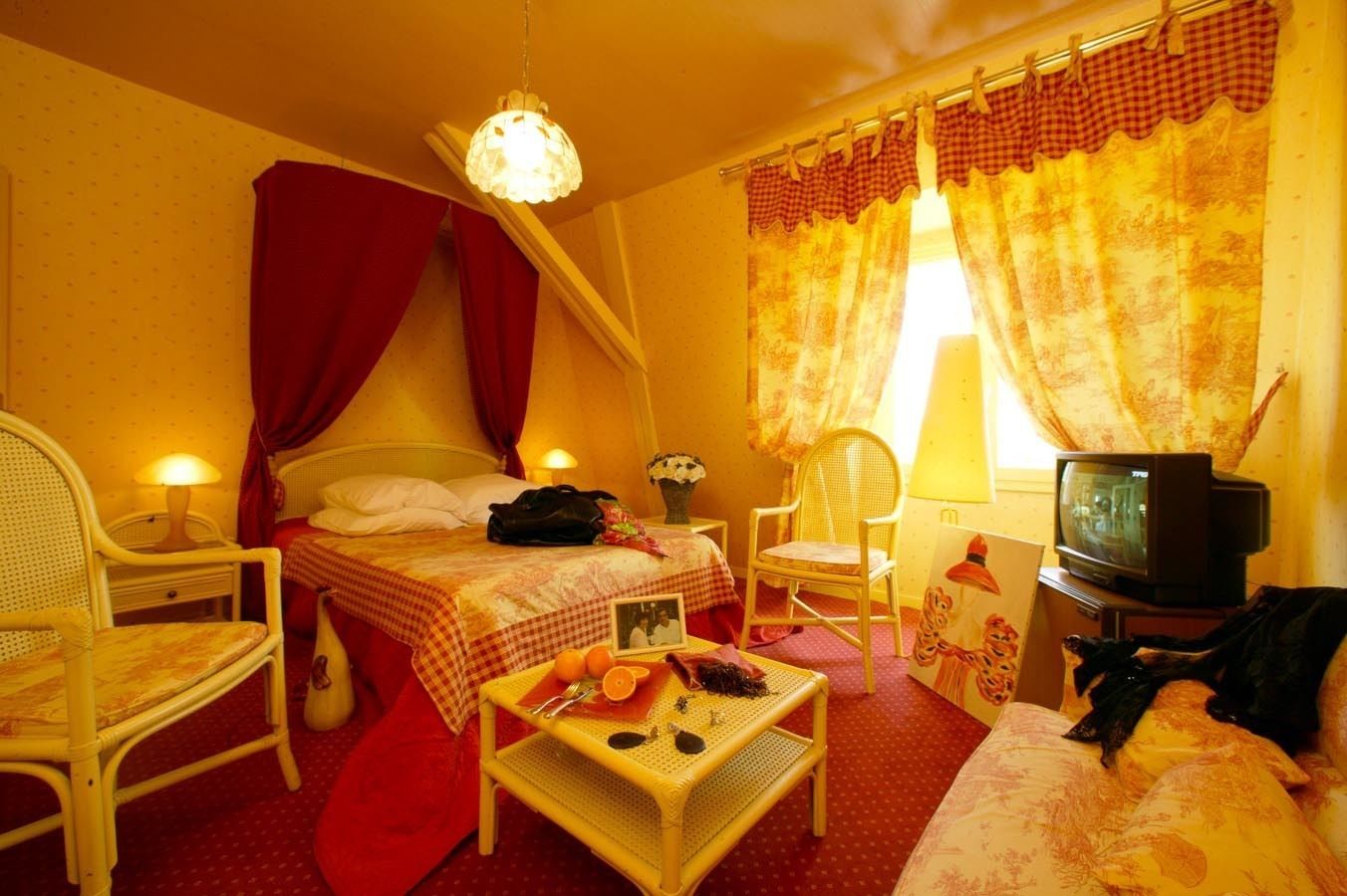 Una habitación acogedora con cama, una silla, una mesita con frutas, televisión y cortinas.