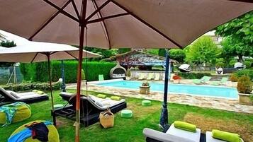 Relax by the pool surrounded by lush greenery and comfortable lounge chairs.