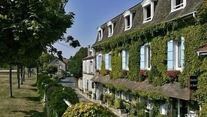 Un hilera de edificios tradicionales de estilo europeo, arquitectura uniforme, una calle estrecha y abundante vegetación.