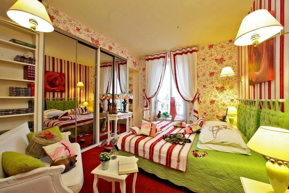 Une chambre confortable avec un lit vert, des rideaux à rayures et une tête de lit rouge et blanche à rayures.