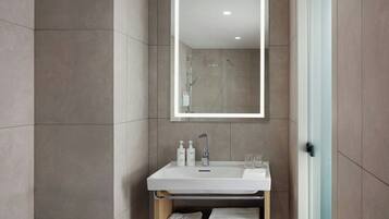 Un baño moderno con un lavabo blanco, dos botellas de champú, un espejo y dos toallas.