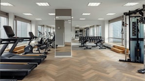 Un gimnasio con cintas de correr, elípticas y equipo de levantamiento de pesas.