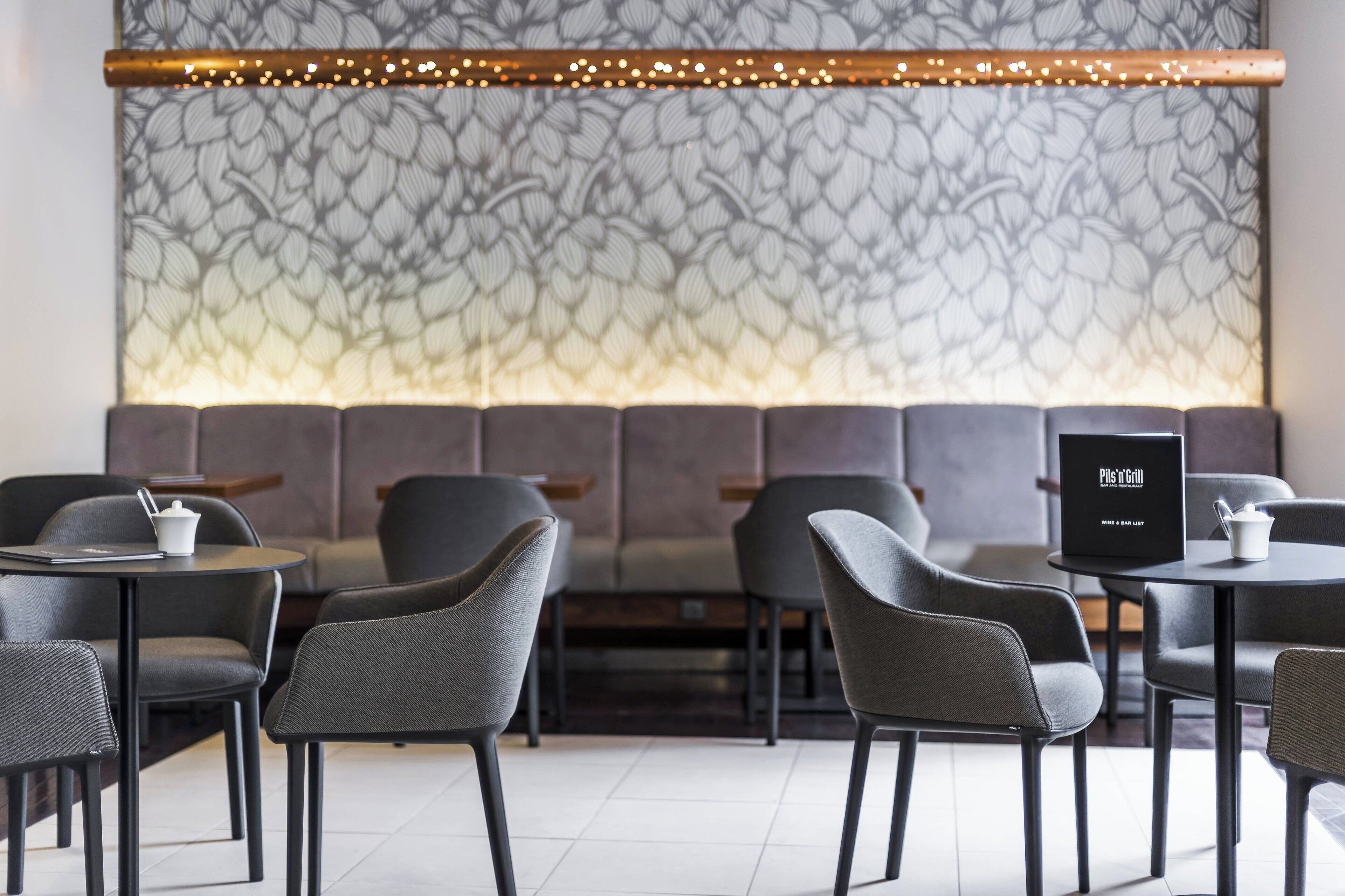 A modern restaurant interior with a patterned wall, cushioned seating, and a menu stand.