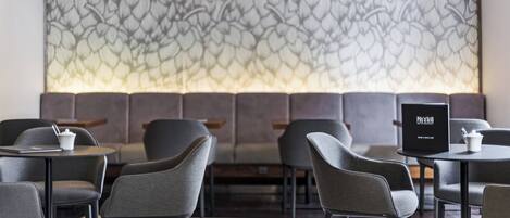 A modern restaurant interior with a patterned wall, cushioned seating, and a menu stand.