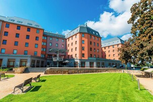 Un hotel de varios pisos con un patio central, asientos al aire libre y una escalera que conduce a la entrada.