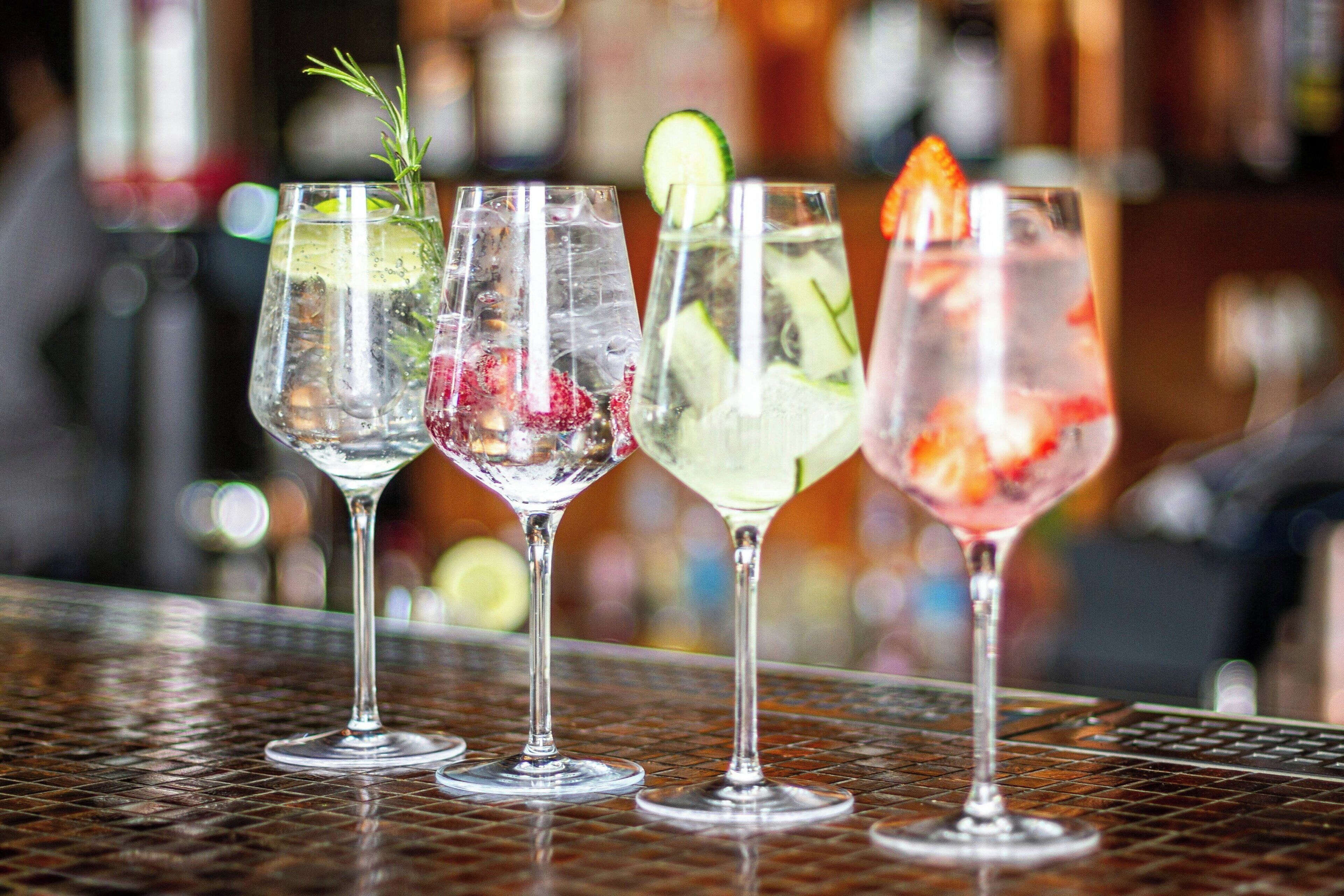 Four glasses of cocktails on a metal table.