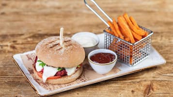A burger with fries and ketchup on a wooden table.