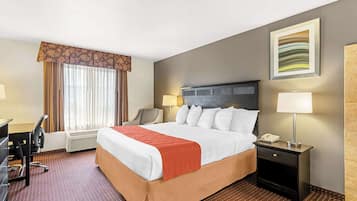 Una habitación de hotel con cama, escritorio, silla y dos lámparas de noche.