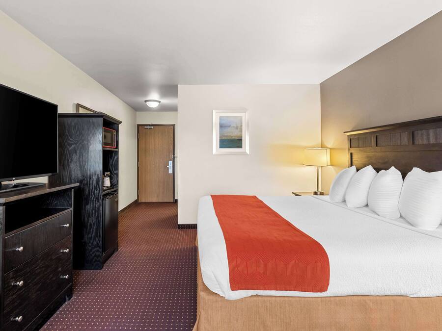 A hotel room with a bed, a TV, a desk, and a wardrobe.