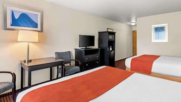 A hotel room with two beds, a desk, a chair, a television, and a cabinet.