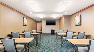 A conference room with a patterned carpet, wooden tables, and grey chairs.