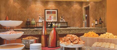 A buffet with various food items including fruits, chips, and cheeses.