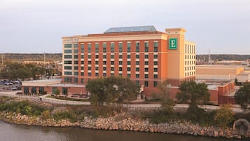 A multi-story hotel with a prominent 'E' logo, situated by a body of water with a stone-lined walkway.