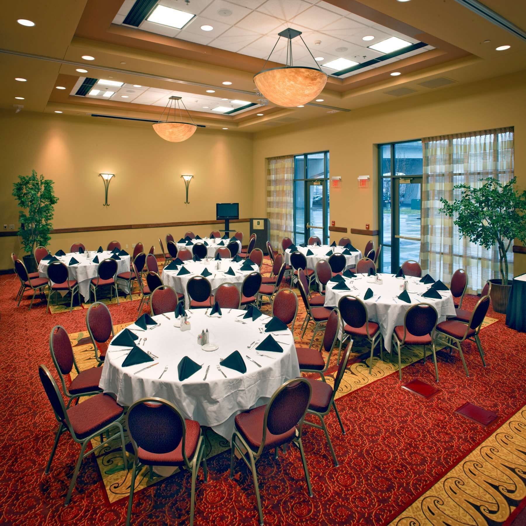 A conference room with multiple round tables, each set with chairs and table settings.