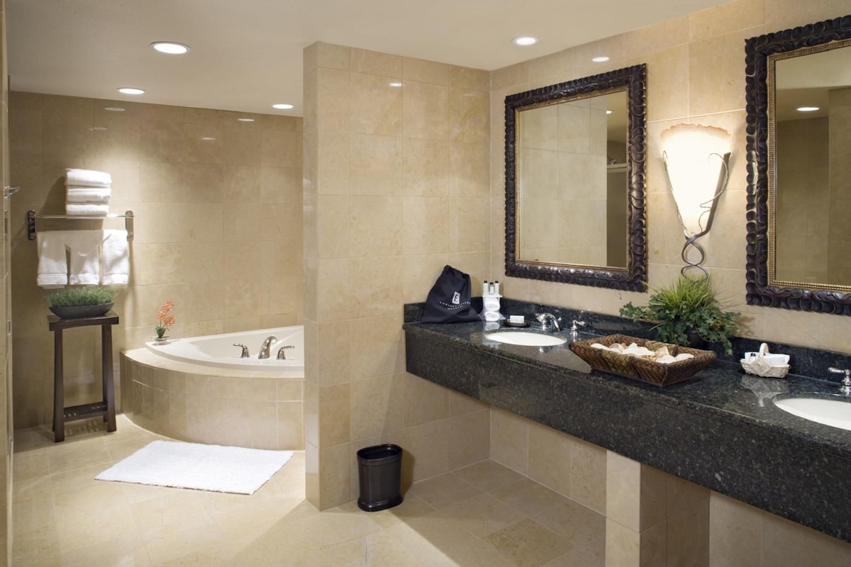 Un baño moderno con bañera, dos lavamanos y un espejo grande.