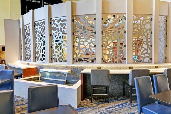 A hotel lobby with a reception desk, seating area, and decorative screens.