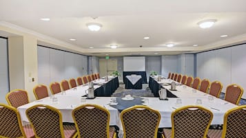 Uma sala de conferências com uma mesa comprida, cadeiras e uma tela de projeção.